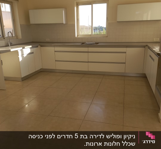 מטבח נקי עם ארונות לבנים ורצפה מבריקה